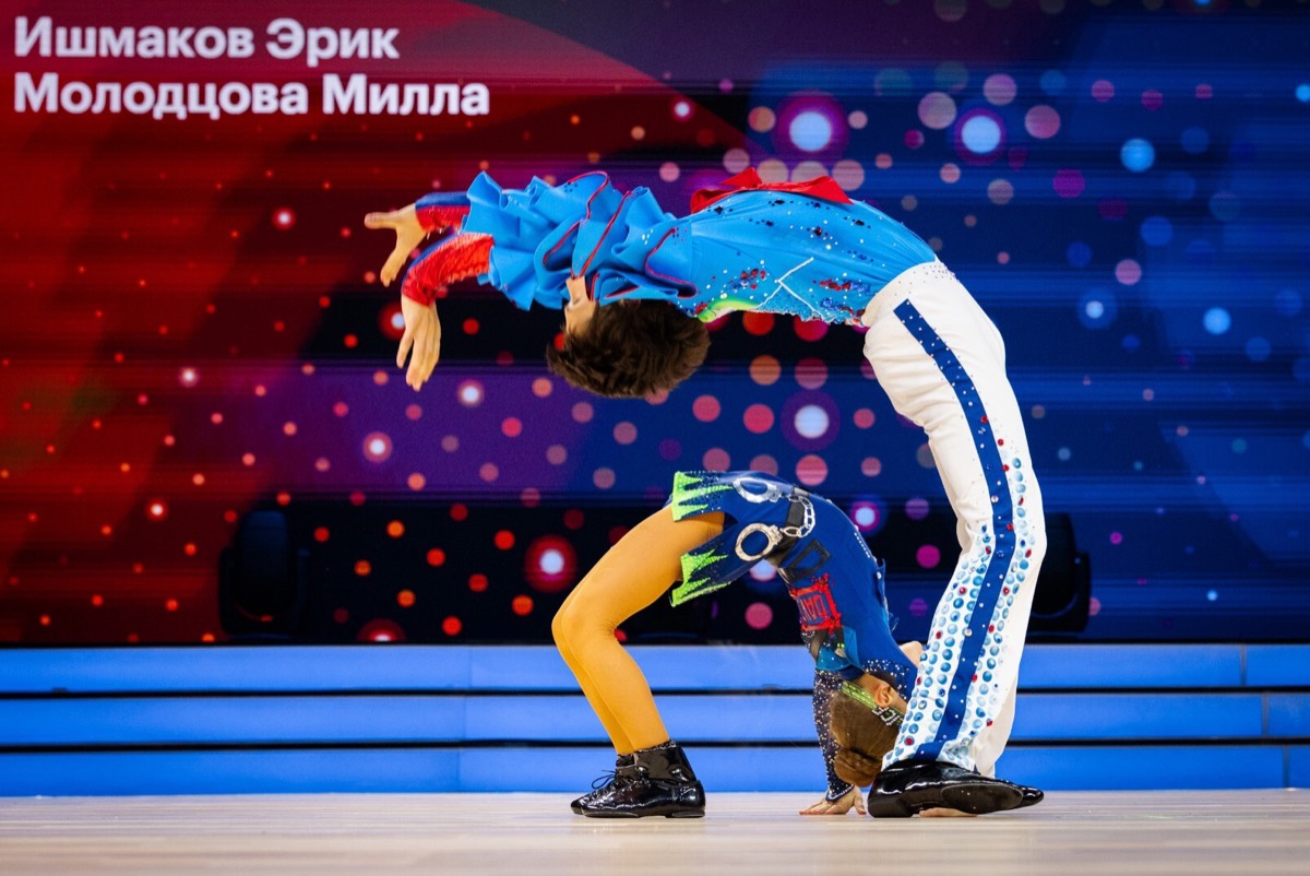 Юные спортсмены клуба выполняют акробатический элемент
